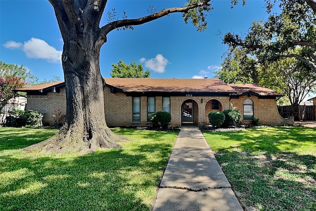 view of front of home featuring a front lawn, fence, and brick siding