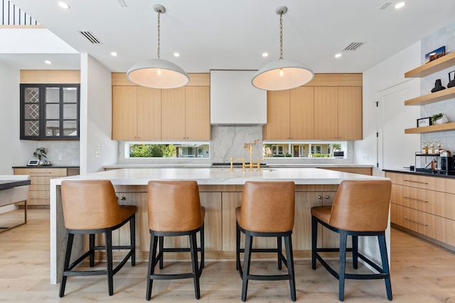 kitchen with hanging light fixtures, light wood-type flooring, and a healthy amount of sunlight