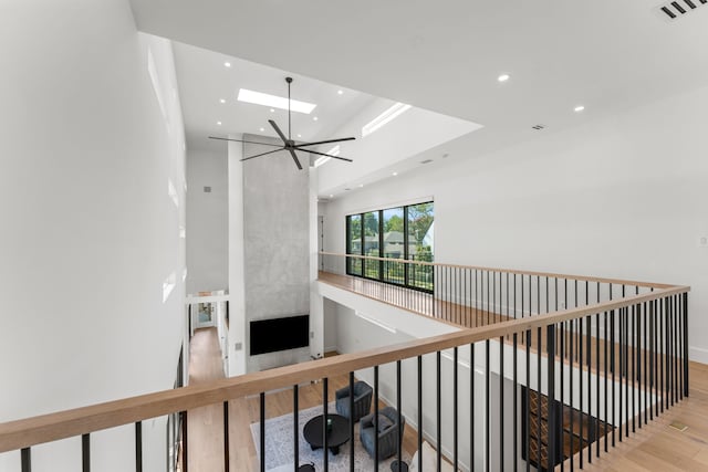 hall featuring a skylight, light wood-type flooring, a tray ceiling, and an inviting chandelier