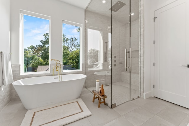 bathroom featuring shower with separate bathtub, tile walls, and tile patterned floors