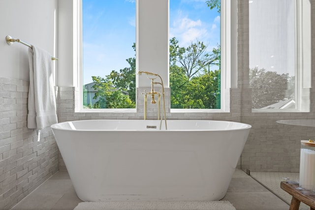 bathroom featuring a tub, tile patterned flooring, and tile walls