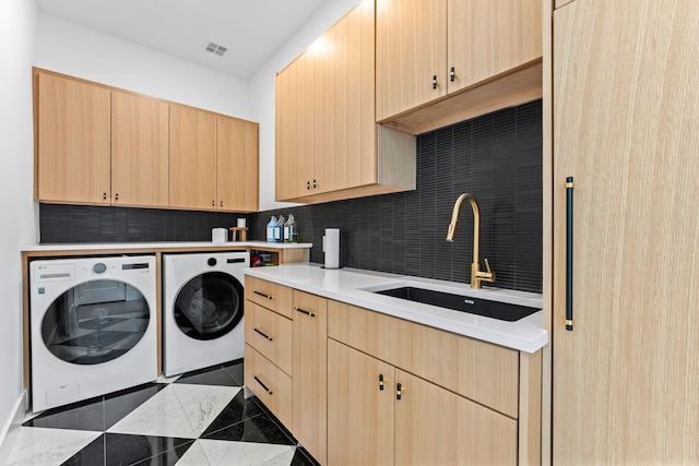 washroom featuring dark tile patterned floors, washer and dryer, sink, and cabinets