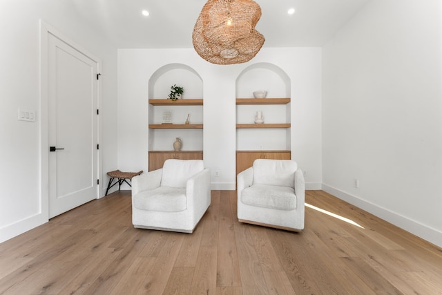 sitting room with built in features and light hardwood / wood-style floors