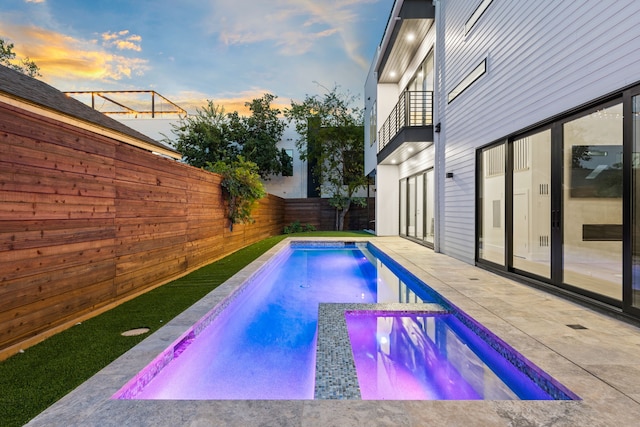 pool at dusk featuring a patio area