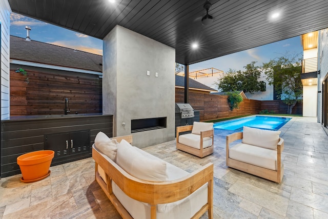 patio terrace at dusk with a fenced in pool, an outdoor hangout area, sink, and grilling area