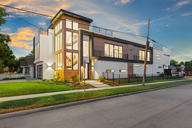 contemporary home with a lawn, a balcony, and a garage