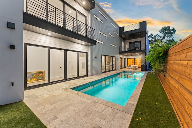 pool at dusk featuring a patio area