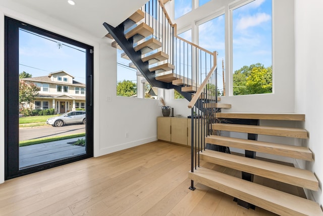 staircase with plenty of natural light and hardwood / wood-style floors