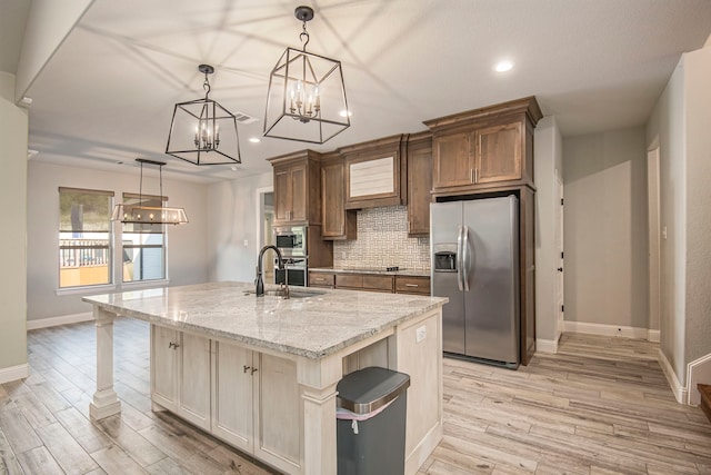 kitchen featuring light stone countertops, stainless steel appliances, a breakfast bar, pendant lighting, and a center island with sink