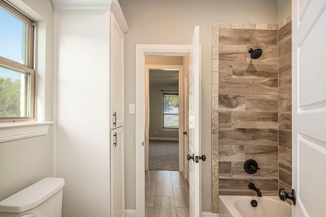 bathroom with tiled shower / bath combo and toilet