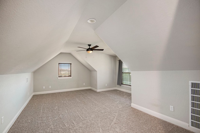 additional living space with lofted ceiling, carpet, a textured ceiling, and ceiling fan