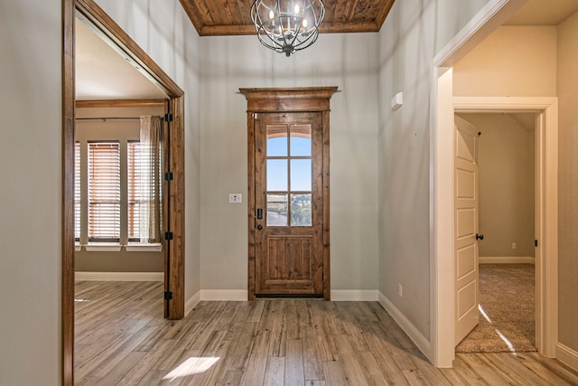 entrance foyer with a notable chandelier, crown molding, wood ceiling, and light hardwood / wood-style flooring