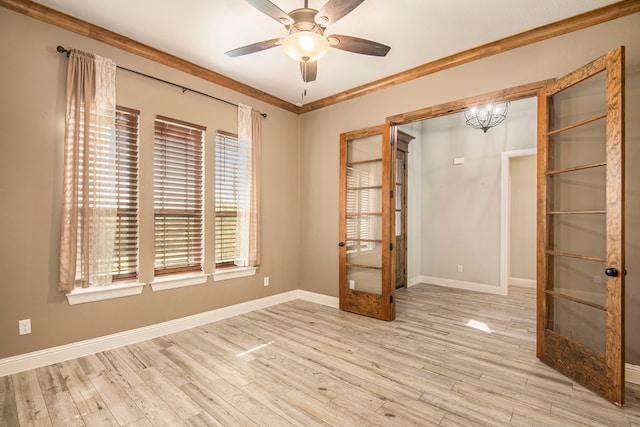 spare room with french doors, ceiling fan with notable chandelier, ornamental molding, and light wood-type flooring