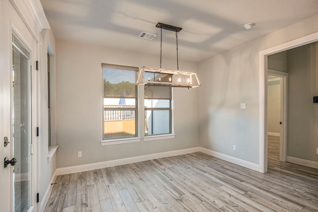 unfurnished dining area featuring a notable chandelier and light hardwood / wood-style floors