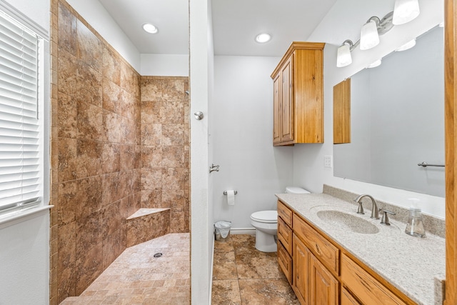 bathroom with vanity, tiled shower, and toilet