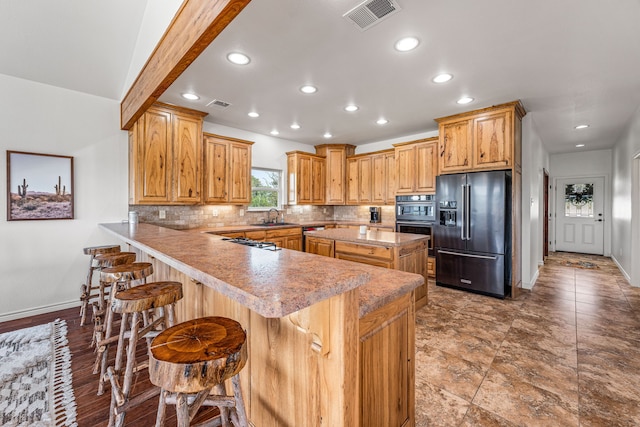 kitchen featuring sink, kitchen peninsula, appliances with stainless steel finishes, a breakfast bar, and decorative backsplash