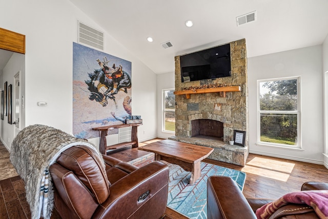 living room featuring a stone fireplace, lofted ceiling, and hardwood / wood-style floors