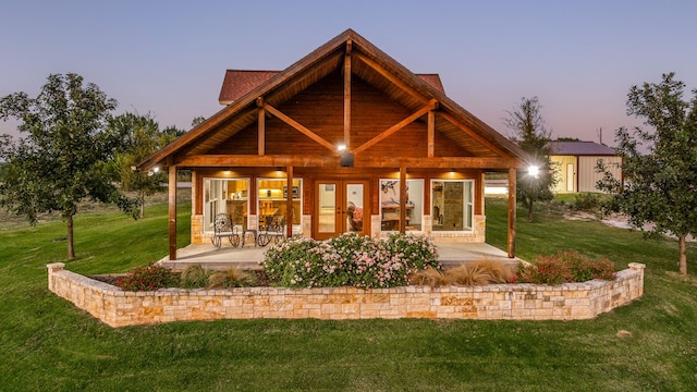 back house at dusk with a storage shed, a yard, and a patio