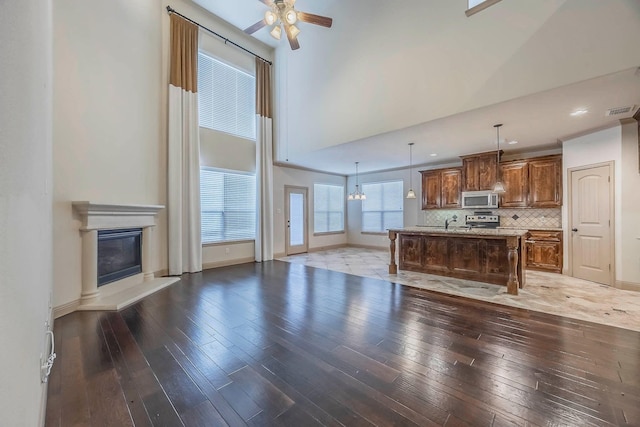 unfurnished living room featuring wood-type flooring, a high ceiling, sink, and ceiling fan