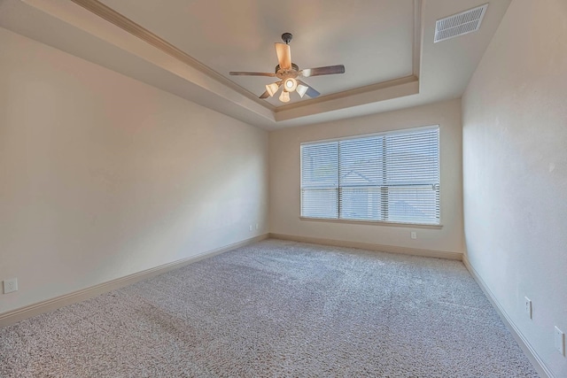 carpeted spare room featuring ceiling fan and a tray ceiling