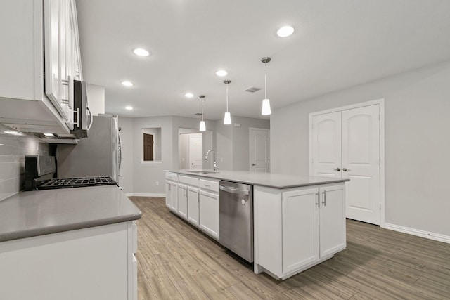 kitchen with pendant lighting, a center island with sink, sink, appliances with stainless steel finishes, and white cabinets