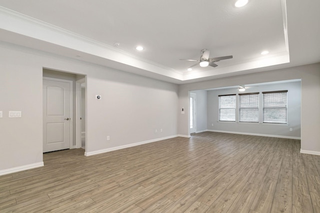 spare room featuring ceiling fan, light hardwood / wood-style flooring, a raised ceiling, and ornamental molding