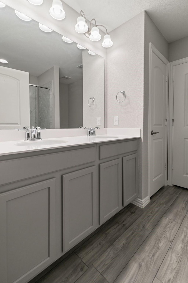 bathroom with a shower with shower door and vanity