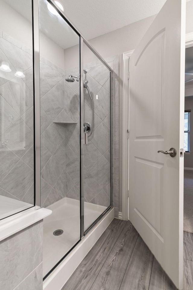 bathroom with wood-type flooring and a shower with door