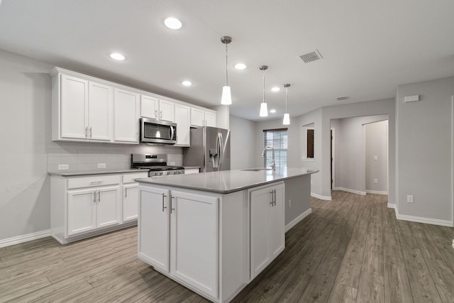 kitchen with white cabinetry, appliances with stainless steel finishes, light wood-type flooring, pendant lighting, and a center island