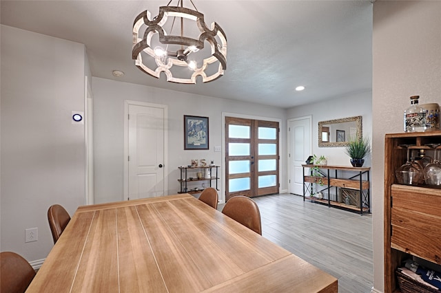 dining space featuring an inviting chandelier, french doors, and light hardwood / wood-style floors