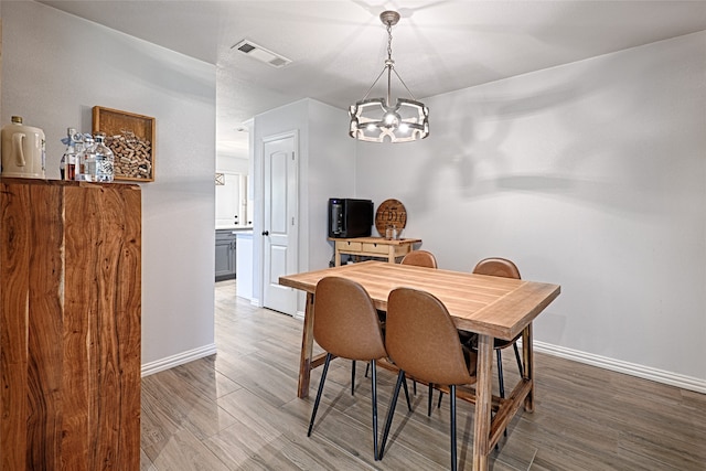 dining room with hardwood / wood-style floors and a chandelier