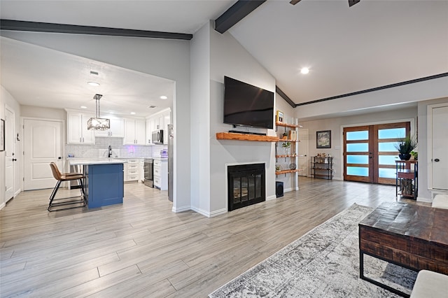 living room with high vaulted ceiling, beamed ceiling, french doors, sink, and light hardwood / wood-style flooring