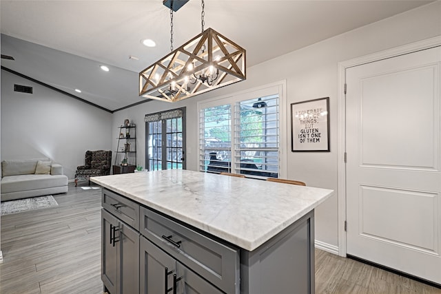 kitchen featuring gray cabinetry, pendant lighting, light hardwood / wood-style floors, and a center island