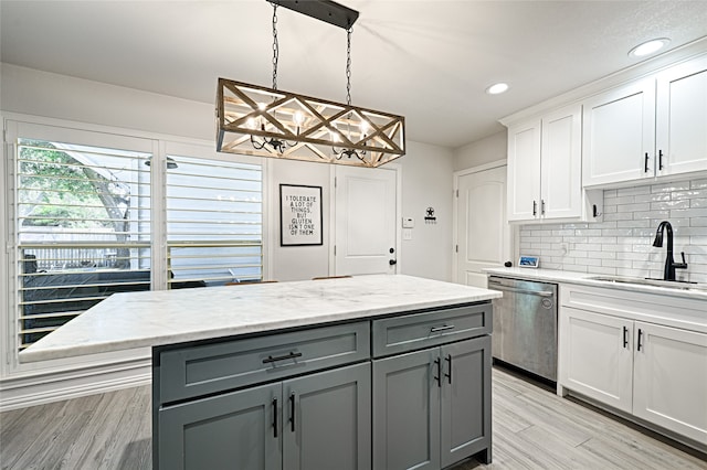 kitchen featuring sink, decorative light fixtures, white cabinetry, dishwasher, and an inviting chandelier