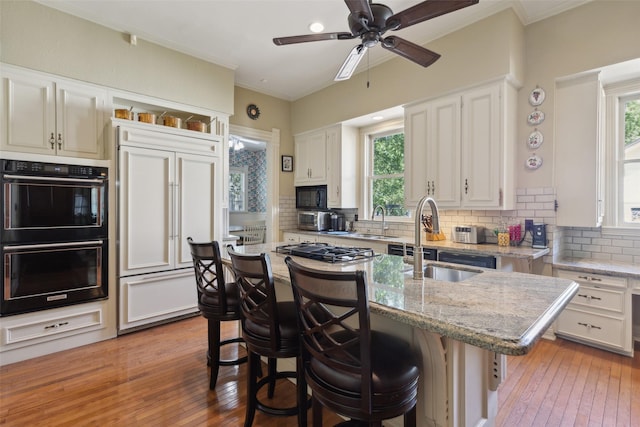 903 N College St, Mckinney, TX 75069 - kitchen featuring black appliances, decorative backsplash, a breakfast bar, and light wood finished floors
