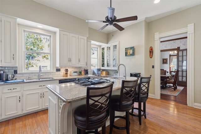 kitchen with sink, white cabinetry, a breakfast bar area, and a center island