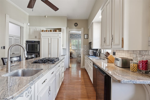 kitchen with light stone countertops, backsplash, sink, and light hardwood / wood-style flooring