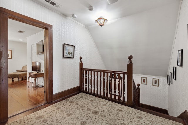 hall with lofted ceiling, ornamental molding, and hardwood / wood-style floors