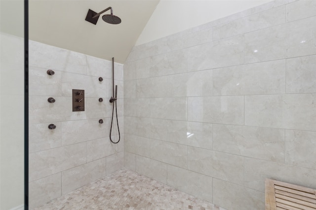 bathroom with lofted ceiling and tiled shower