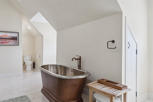 bathroom featuring lofted ceiling, a bathing tub, and toilet