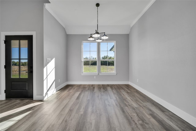 unfurnished dining area with hardwood / wood-style flooring, ornamental molding, and a notable chandelier