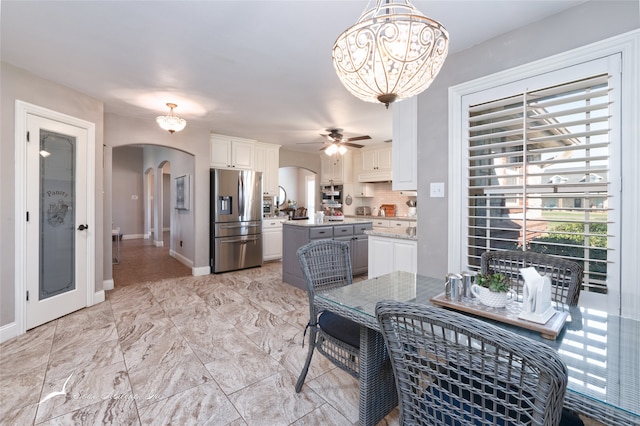 dining space featuring ceiling fan with notable chandelier