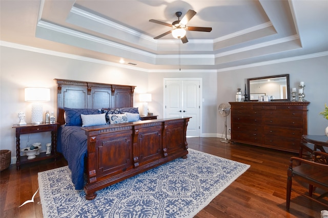 bedroom featuring ceiling fan, a tray ceiling, dark hardwood / wood-style floors, a closet, and crown molding