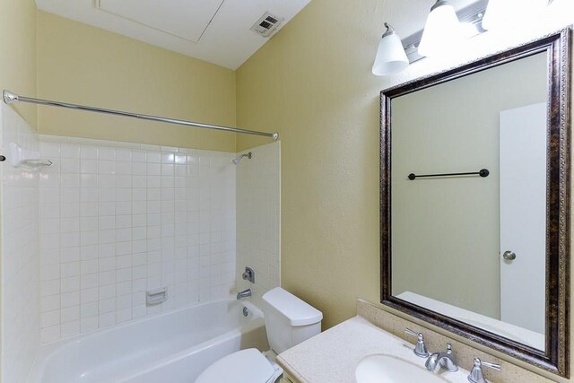 full bathroom featuring tiled shower / bath, vanity, and toilet