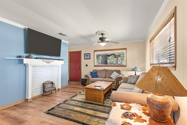 living room with wood walls, light hardwood / wood-style floors, crown molding, and ceiling fan