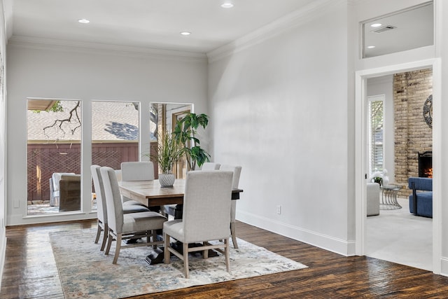 dining space featuring dark hardwood / wood-style floors, a brick fireplace, and crown molding