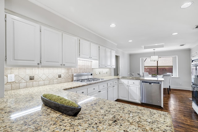 kitchen with kitchen peninsula, appliances with stainless steel finishes, sink, white cabinets, and hanging light fixtures