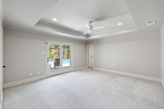 carpeted spare room featuring ceiling fan, ornamental molding, and a tray ceiling