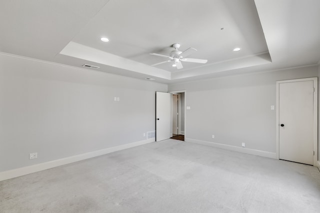 carpeted empty room featuring a tray ceiling, ceiling fan, and crown molding