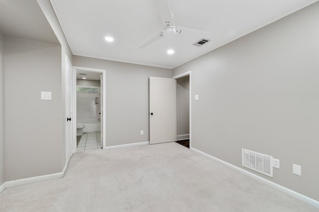 unfurnished bedroom with ceiling fan, light colored carpet, and ensuite bath